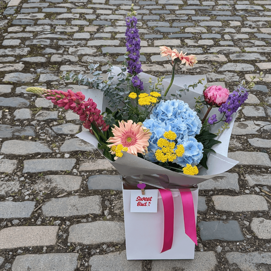 bright, colourful, modern flower bouquet in a white gift bag